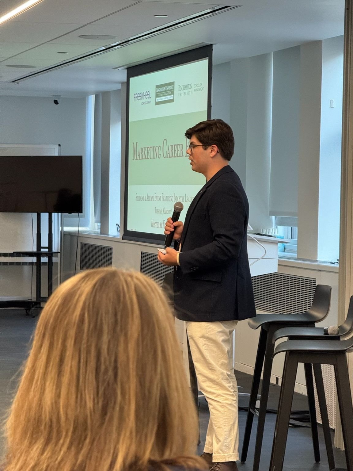 Eric Hirsh presenting with a microphone in front of an audience at a marketing careers event